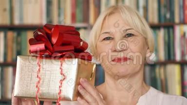 有礼物的高级女人。 领取养老金的人拿着红色丝带的金色<strong>礼盒</strong>庆祝<strong>生日</strong>